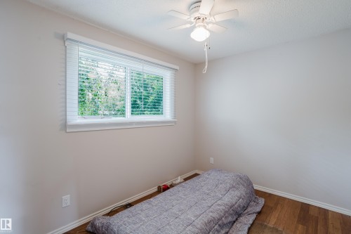 Room featuring wood-finish flooring, a white ceiling fan with integrated lighting, and a window with horizontal blinds - 212 Homestead Crescent, Edmonton, AB 