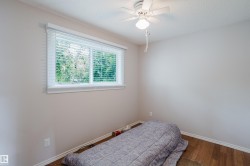 Room featuring wood-finish flooring, a white ceiling fan with integrated lighting, and a window with horizontal blinds - 