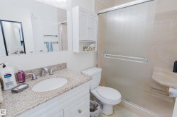 Bathroom featuring a vanity with a granite-style countertop and undermount sink, chrome fixtures, a mirrored medicine cabinet, and a shower enclosure with a sliding frosted glass door - 