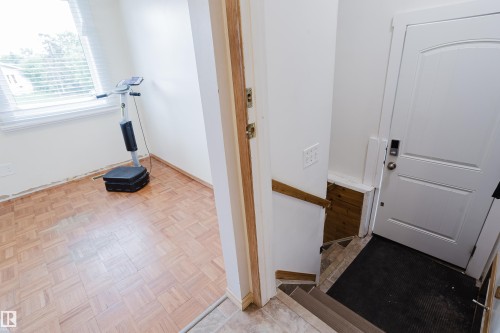Entryway featuring a white paneled door with digital lock, a wooden handrail, and staircase with tile risers - 212 Homestead Crescent, Edmonton, AB 