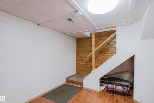 Staircase featuring wood plank accent wall, white risers, and wood-finish flooring - 212 Homestead Crescent, Edmonton, AB 