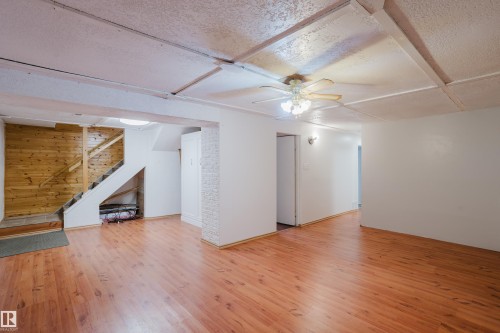 Finished basement space featuring wood-finish flooring, white painted walls, and a recessed ceiling with exposed beams - 212 Homestead Crescent, Edmonton, AB 