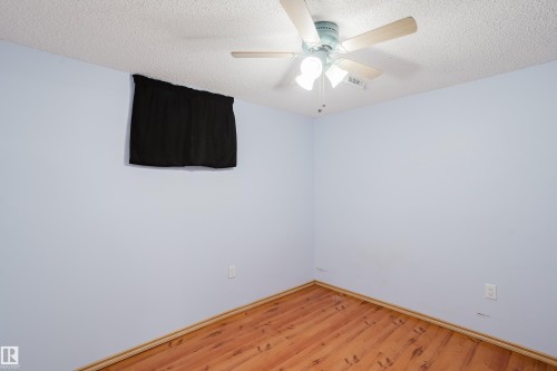 Room featuring wood-finish flooring, light blue walls, and a textured white ceiling - 212 Homestead Crescent, Edmonton, AB 