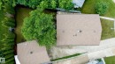 Property featuring a shingle roof, a paved driveway, and established landscaping including a large tree and evergreen bushes - 212 Homestead Crescent, Edmonton, AB 