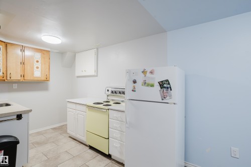 Kitchen area featuring light wood-finish upper cabinetry, white lower cabinetry, and a light-colored countertop - 212 Homestead Crescent, Edmonton, AB 