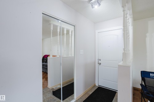 Entryway featuring a white paneled door, track lighting, and a partial baluster wall - 212 Homestead Crescent, Edmonton, AB 