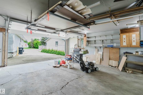 Attached garage featuring an overhead storage system, integrated wall shelving, two built-in cabinets, and a concrete floor - 212 Homestead Crescent, Edmonton, AB 