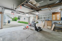 Attached garage featuring an overhead storage system, integrated wall shelving, two built-in cabinets, and a concrete floor - 