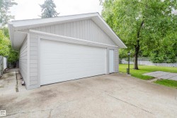 Detached two-car garage with light gray siding, white trim, and a white panel garage door - 