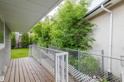 Covered wooden deck with white railing, overlooking a fenced yard with mature trees - 212 Homestead Crescent, Edmonton, AB 