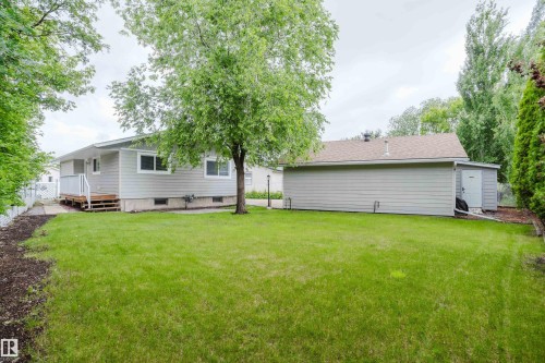 Spacious lawn area featuring a light gray siding residence with white trim windows and an accompanying detached garage with a side storage shed - 212 Homestead Crescent, Edmonton, AB 