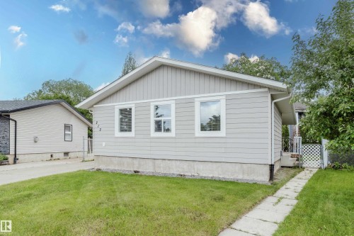 Ranch-style exterior with light gray siding, white trim windows, and a concrete foundation - 212 Homestead Crescent, Edmonton, AB 