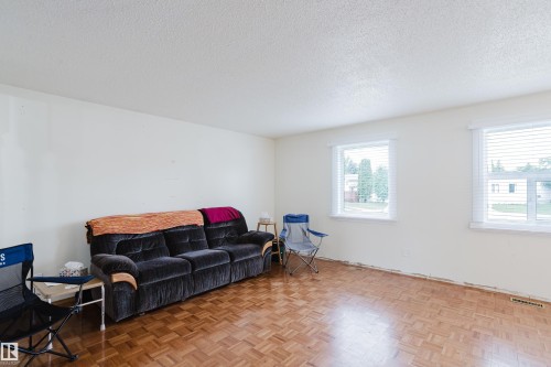 Living area featuring natural light, parquet wood-finish flooring, textured ceilings, and white walls - 212 Homestead Crescent, Edmonton, AB 