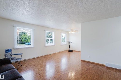 Living area with wood-finish flooring, white walls, and multiple windows with blinds - 212 Homestead Crescent, Edmonton, AB 
