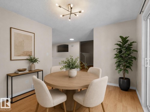 Open-concept dining area featuring wood-finish flooring, a contemporary ceiling light fixture, neutral wall finishes, and a sliding glass door - 1855 Mill Woods Rd E Nw, Edmonton, AB 