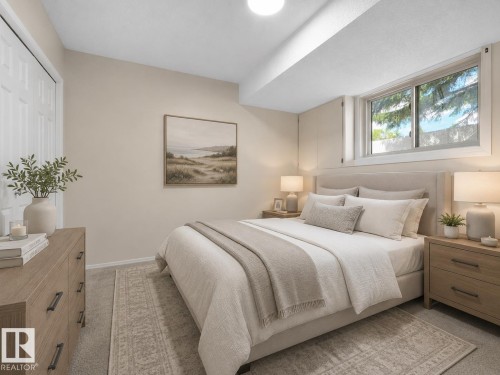 Carpeted bedroom featuring a window, built-in overhead lighting, light-toned walls, and a white bi-fold closet door - 1855 Mill Woods Rd E Nw, Edmonton, AB 