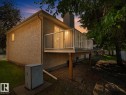 Exterior stucco finish with a raised deck featuring white railings, sliding glass door access, and a concrete foundation - 1855 Mill Woods Rd E Nw, Edmonton, AB 