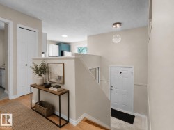 Foyer featuring light-toned walls, wood-finish flooring, a contemporary chandelier, and a white paneled door - 