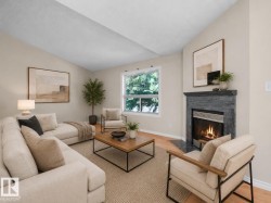 Living area featuring a gas fireplace with a dark stone surround and hearth, vaulted ceiling, and hardwood-style flooring - 