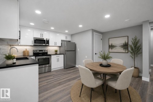 Kitchen featuring white cabinetry, stainless steel appliances, dark countertops, and a white subway tile backsplash - 714 Ebbers Place, Edmonton, AB 