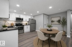 Kitchen featuring white cabinetry, stainless steel appliances, dark countertops, and a white subway tile backsplash - 
