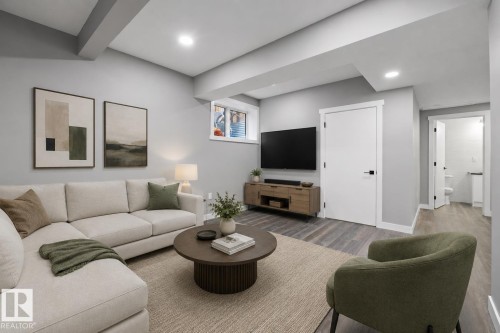 Spacious living area featuring light gray walls, recessed lighting, wood-finish flooring, a contemporary window, and a white interior door with black hardware - 714 Ebbers Place, Edmonton, AB 
