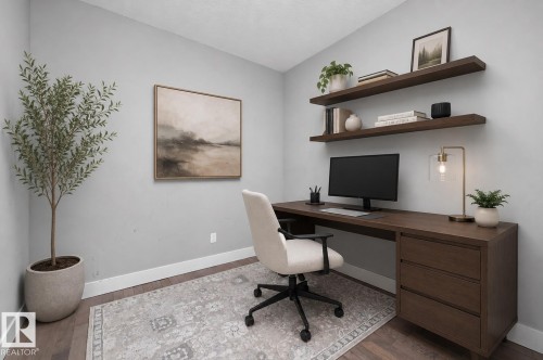 Dedicated workspace featuring wood-finish flooring, two floating wall shelves, a built-in desk with integrated drawers, and ample natural light - 714 Ebbers Place, Edmonton, AB 