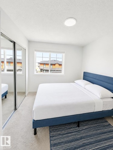 Carpeted room featuring a large window, a ceiling-mounted light fixture, and mirrored sliding closet doors - 22845 84 Avenue, Edmonton, AB 