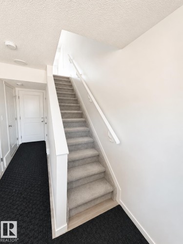 Carpeted staircase with white handrails and a wood-finish landing - 22845 84 Avenue, Edmonton, AB 