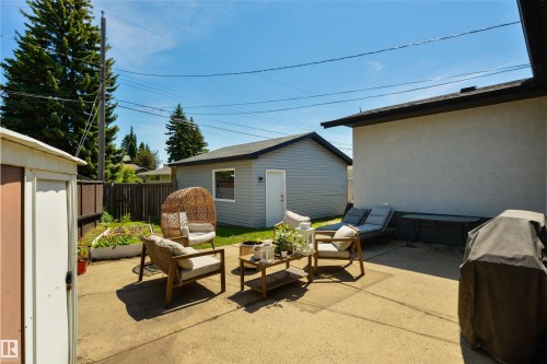 Concrete patio featuring a detached garage with gray siding, a white service door, and a single window - 8917 162 Street, Edmonton, AB 