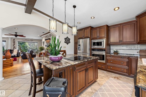 Kitchen island featuring a cooktop, granite countertop, and pendant lighting - 11124 110A Avenue Nw, Edmonton, AB 