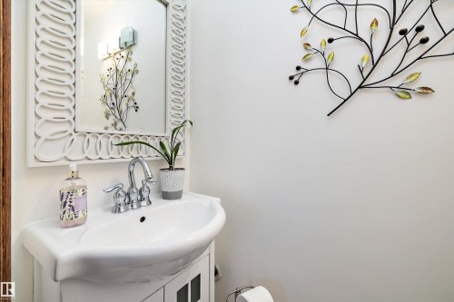 Pedestal sink with chrome faucet, framed by a decorative mirror and wall sconces - 11124 110A Avenue Nw, Edmonton, AB 