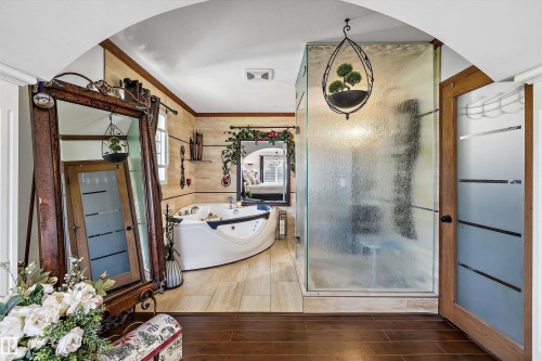 Expansive bathroom featuring a corner jetted soaking tub, a stand-alone shower with obscured glass walls, and tile flooring - 11124 110A Avenue Nw, Edmonton, AB 