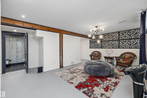 Open concept lower level featuring light gray flooring, exposed timber beams, a decorative wall panel, and recessed lighting - 11124 110A Avenue Nw, Edmonton, AB 