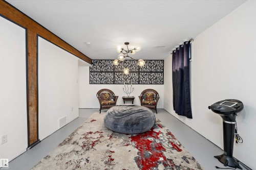 Finished room featuring exposed wood beam accents, modern chandelier, and decorative wall paneling - 11124 110A Avenue Nw, Edmonton, AB 