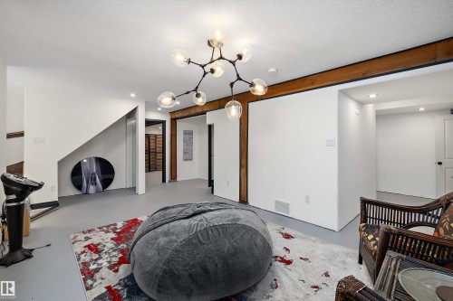Spacious room featuring exposed wood beams, recessed lighting, and a contemporary multi-bulb chandelier - 11124 110A Avenue Nw, Edmonton, AB 