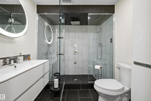 Modern bathroom featuring a glass-enclosed shower with two shower heads, a built-in shower bench, and dark hexagonal tile ceiling - 11124 110A Avenue Nw, Edmonton, AB 