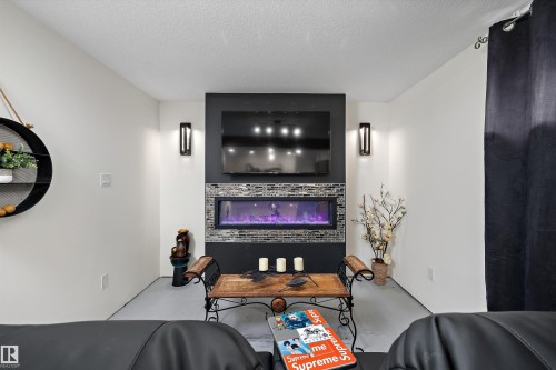 Integrated linear electric fireplace with stone-tile surround and wall-mounted television - 11124 110A Avenue Nw, Edmonton, AB 