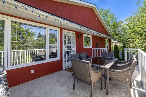 Outdoor deck featuring a textured red exterior, multiple windows with white trim, and white railing - 11124 110A Avenue Nw, Edmonton, AB 