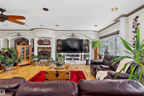 Spacious living area featuring wood-finish flooring, a built-in fireplace with a stone surround, and an integrated entertainment center - 11124 110A Avenue Nw, Edmonton, AB 