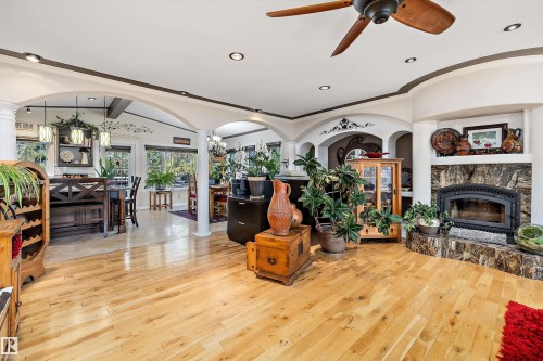 Spacious interior featuring wood-finish flooring, a built-in fireplace with a stone surround, and recessed lighting - 11124 110A Avenue Nw, Edmonton, AB 