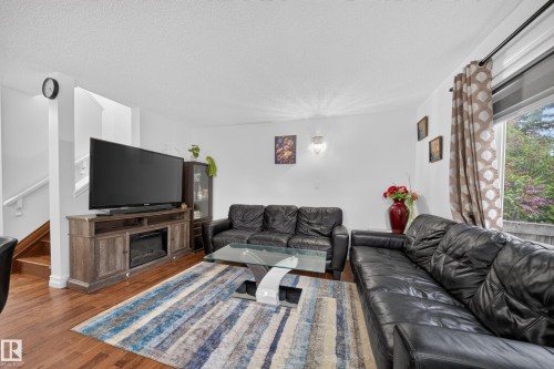 Living area featuring wood-finish flooring and white walls - 4 4350 23 Street, Edmonton, AB 
