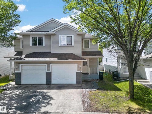 Two-story residence featuring light gray siding, a dark shingle roof, and a two-car attached garage - 4 4350 23 Street, Edmonton, AB 