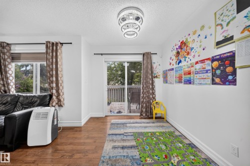 Living space featuring wood-finish flooring, white walls, and a contemporary ceiling fixture - 4 4350 23 Street, Edmonton, AB 