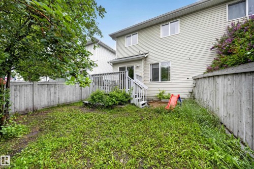 Rear exterior featuring a wooden deck with railing, stairs, and a sliding glass door - 4 4350 23 Street, Edmonton, AB 