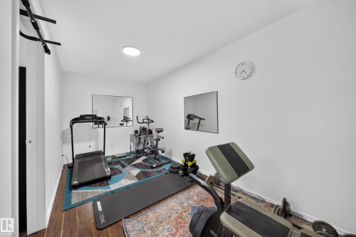 Versatile room featuring wood-finish flooring, white walls, and a circular ceiling light fixture - 4 4350 23 Street, Edmonton, AB 