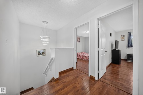 Upper level hallway featuring wood-finish flooring and a contemporary tiered chandelier - 4 4350 23 Street, Edmonton, AB 