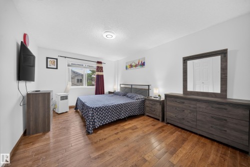 Room featuring wood-finish flooring, white painted walls, and a window with dark-toned curtain rods - 4 4350 23 Street, Edmonton, AB 
