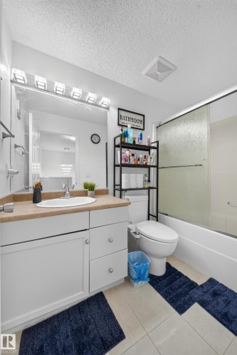 Bathroom featuring a white vanity with a tan countertop, an undermount sink, and a wall-mounted mirror with integrated lighting - 4 4350 23 Street, Edmonton, AB 