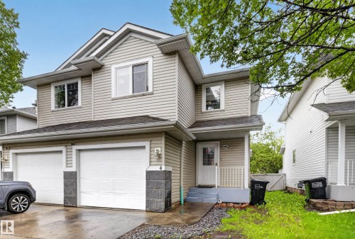 Two-story residence featuring light-toned horizontal siding, a twin garage with white doors, and a covered entry - 4 4350 23 Street, Edmonton, AB 